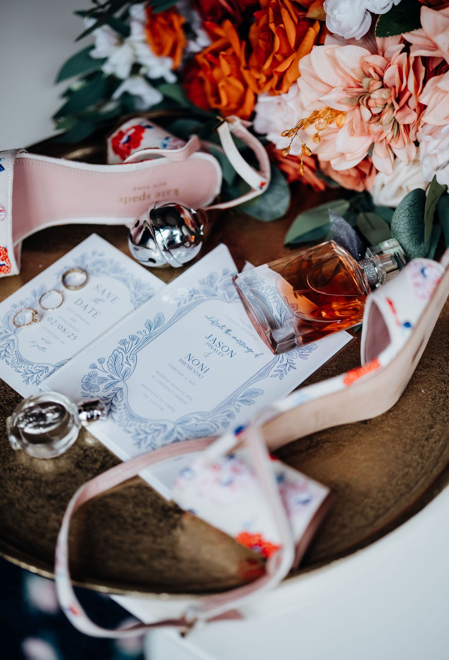 Wedding details including pink shoes, invitations, and orange and pink flowers artistically arranged.