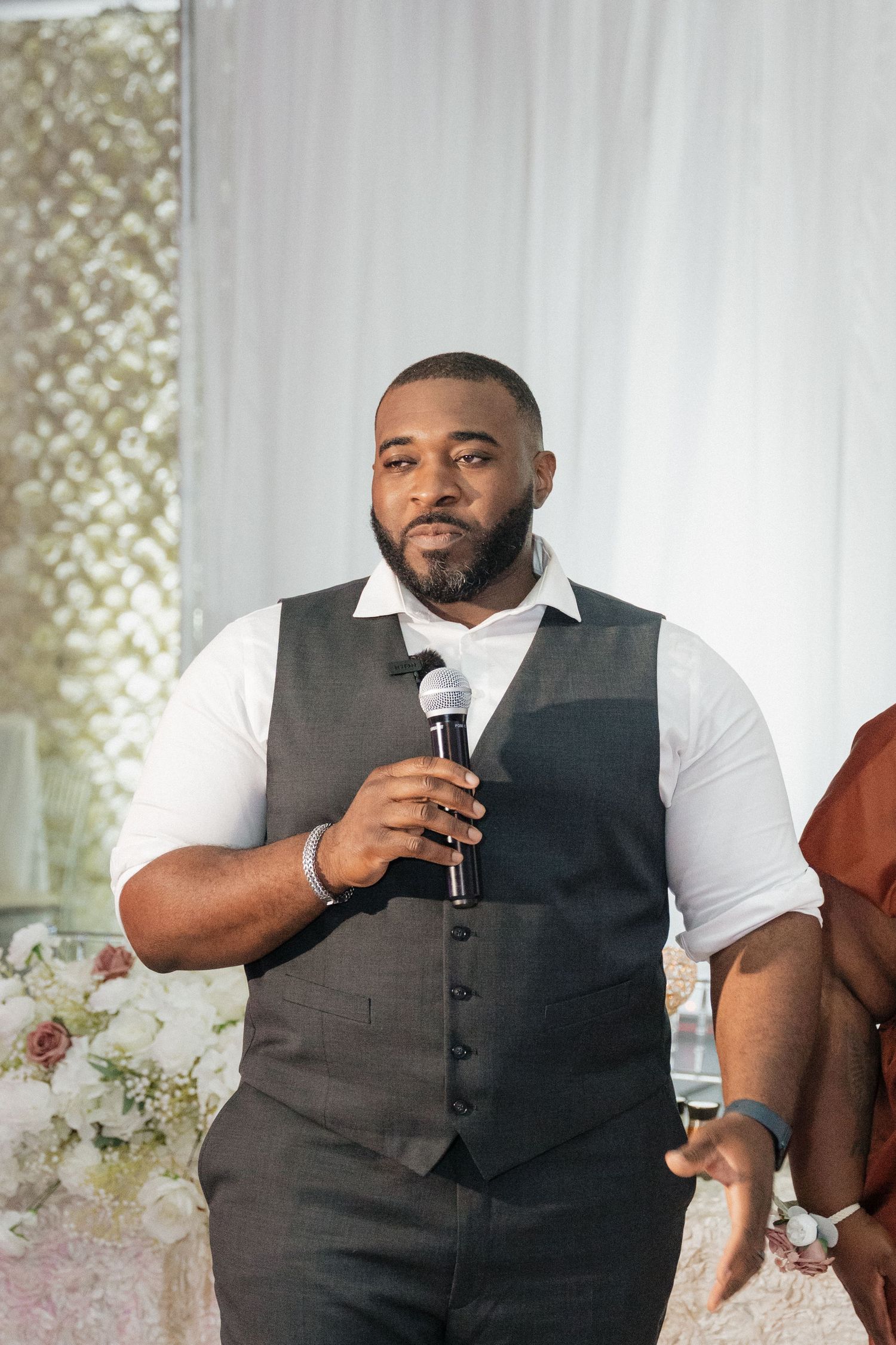 Wedding speaker delivers emotional speech while holding microphone during reception.