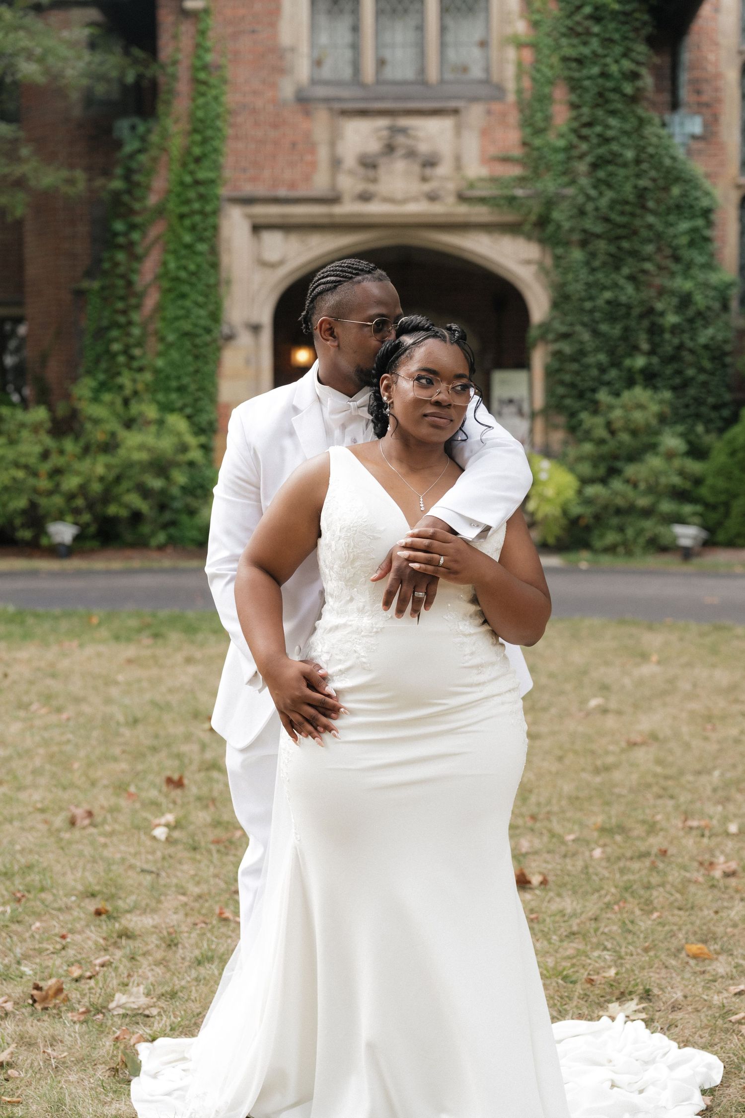 Newlyweds share an intimate moment while dancing together in front of an ivy-covered brick building.