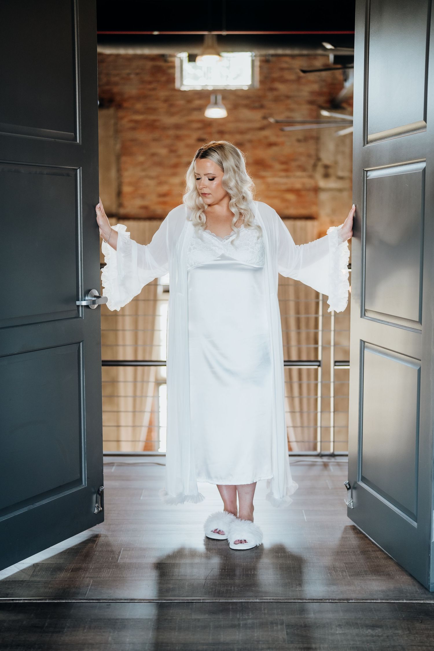A bride in a flowing white dress walks through a series of modern black doorways.