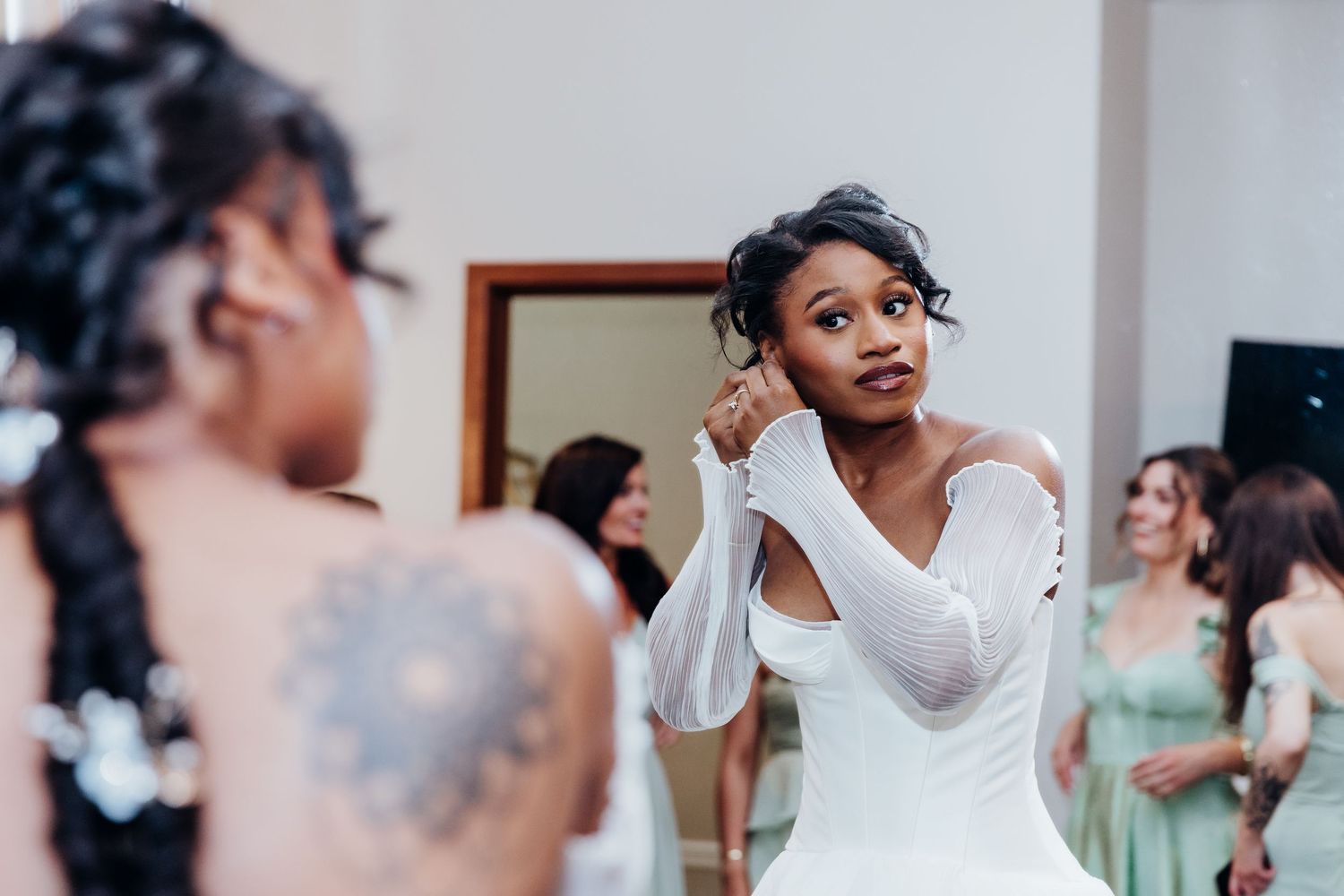 Wedding preparations showing a person getting ready in a white dress with natural lighting.