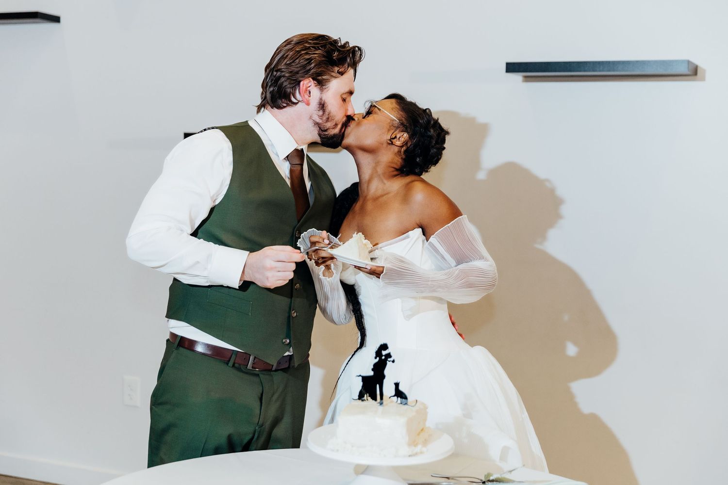 A romantic wedding dance moment captured against a white wall.