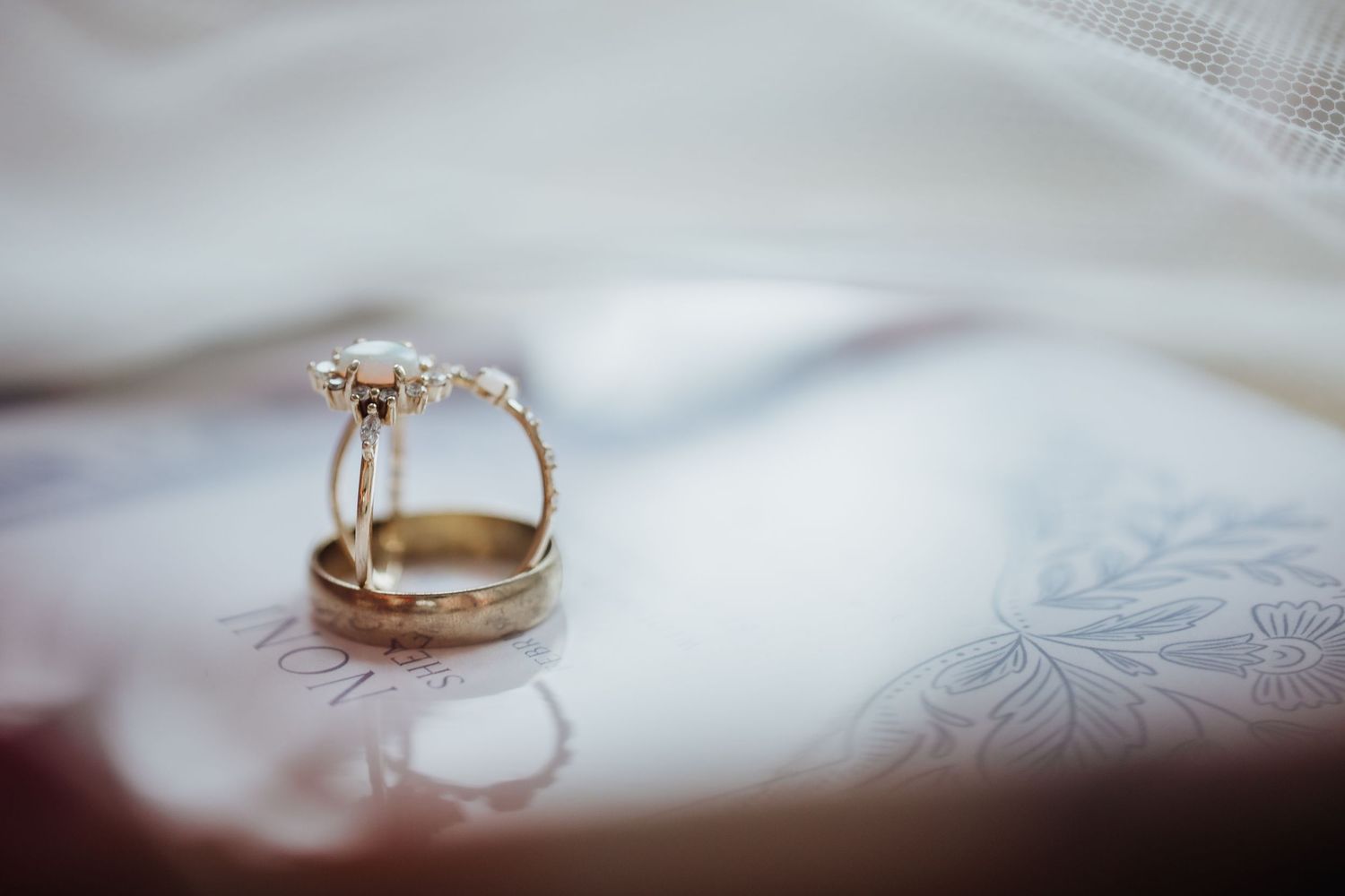 Wedding rings placed on white fabric with delicate lace detailing.