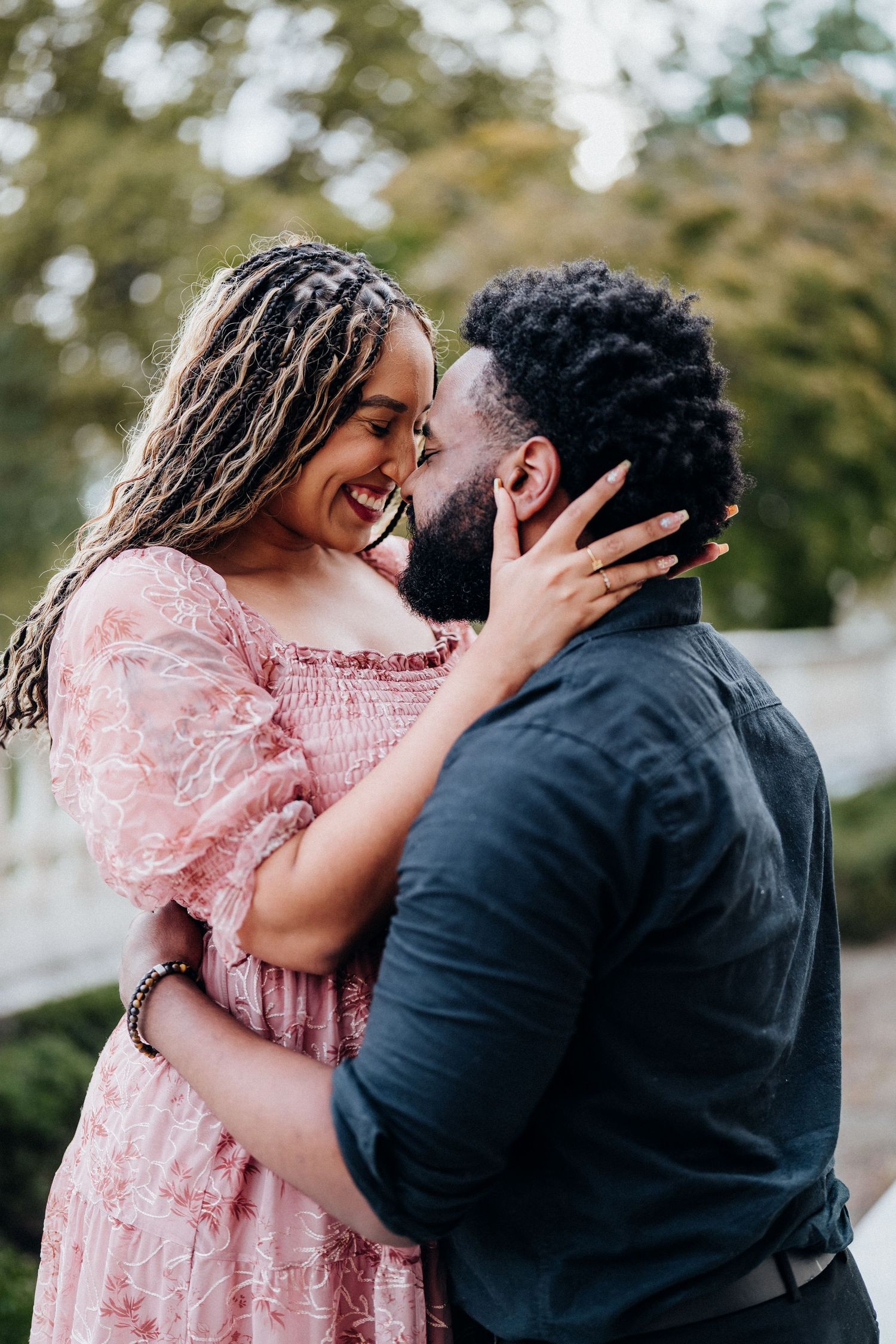 A couple shares an intimate moment outdoors while wearing pink and black attire.