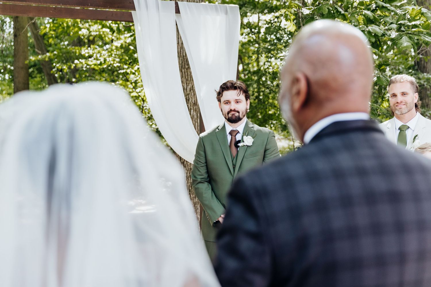 Wedding ceremony guests seated in white chairs during outdoor garden celebration.