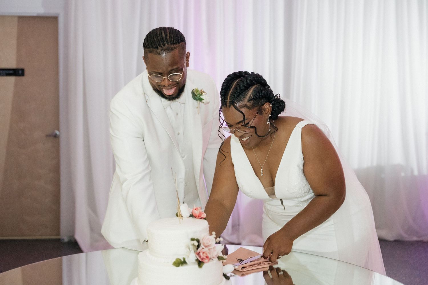 Wedding couple signing documents at a white-draped table during their ceremony.