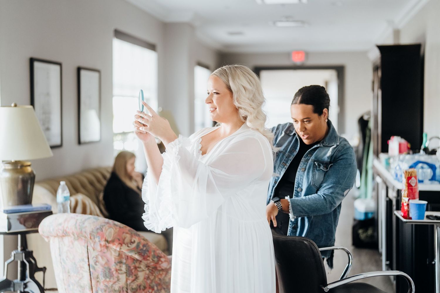 Wedding preparation scene showing various people getting ready in a bright indoor space with white decor.