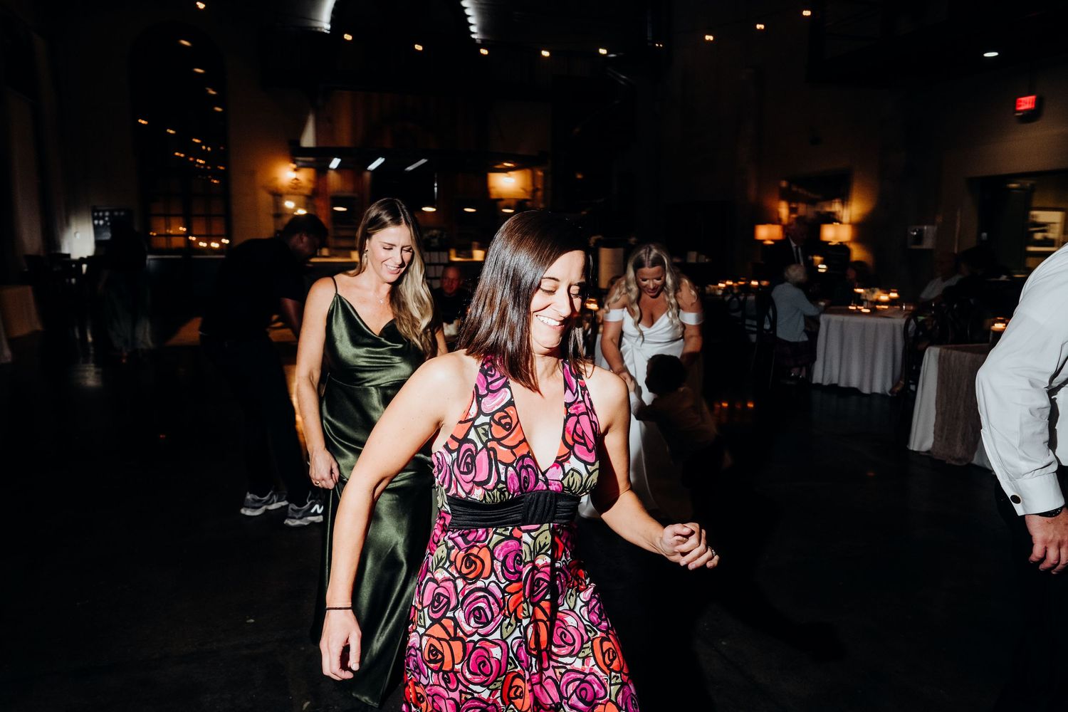 Wedding reception dance floor with guests dancing in a dimly lit venue.