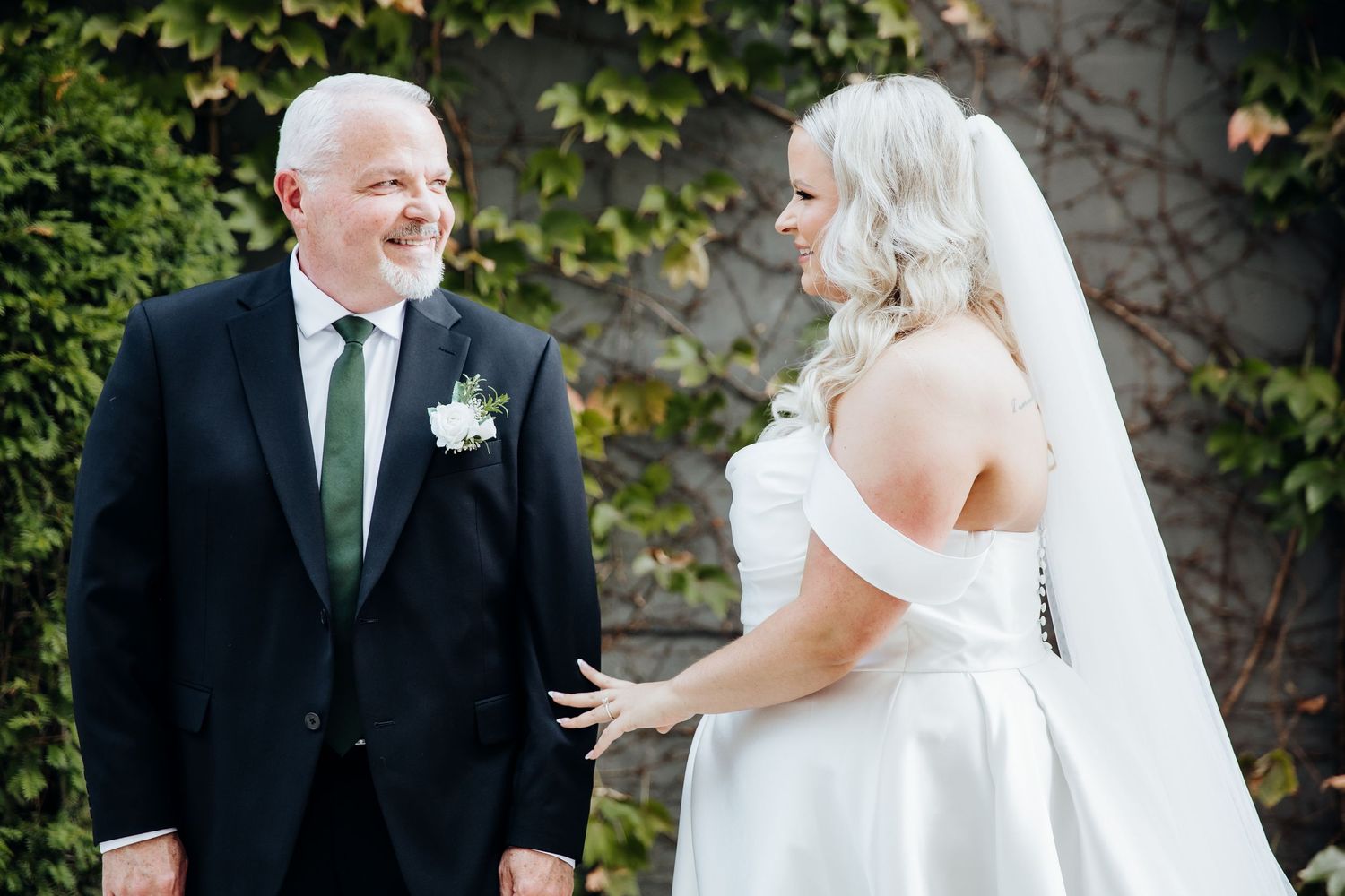 A joyful wedding couple shares an emotional first look moment in a garden setting.