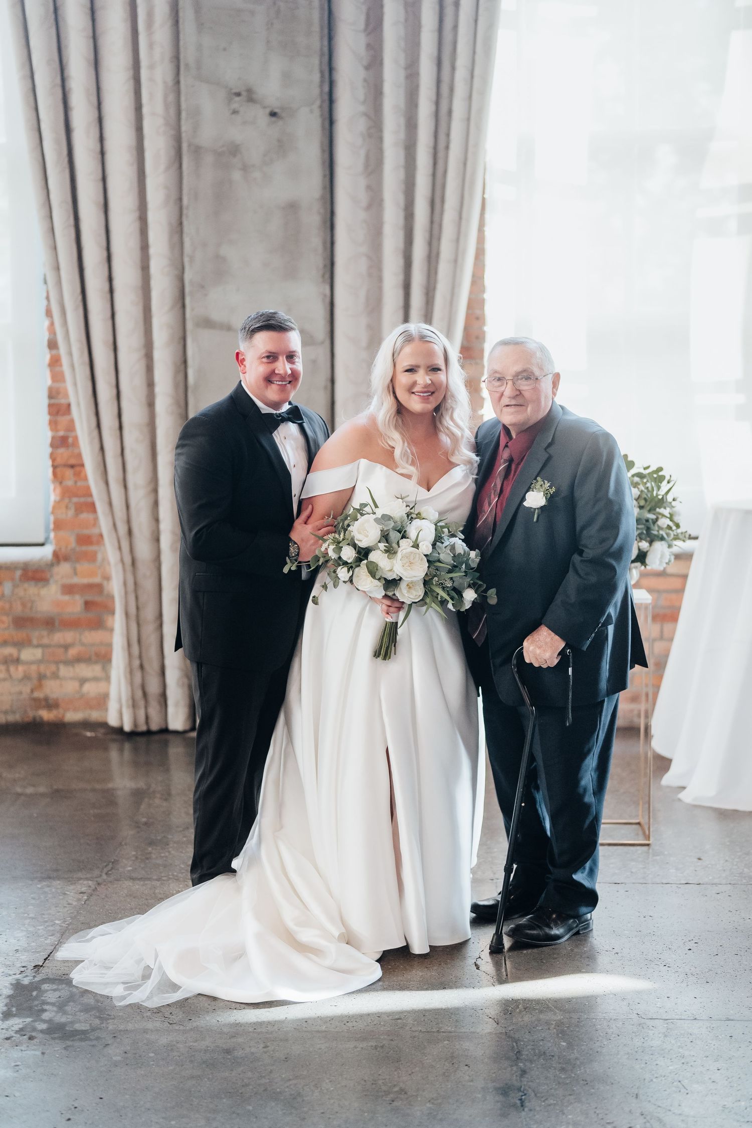 Emotional first look moment captured in a bright industrial venue with exposed brick walls.