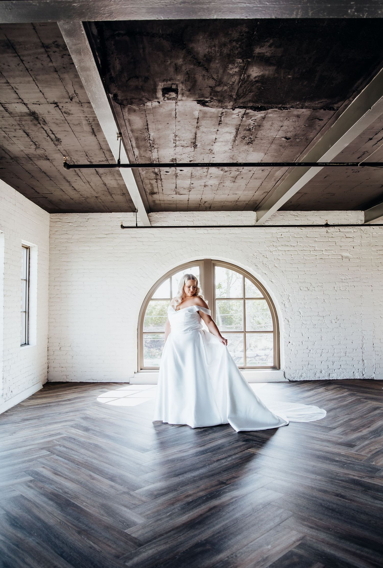 Artistic bridal portraits on a chevron floor in an industrial loft space with white brick walls.