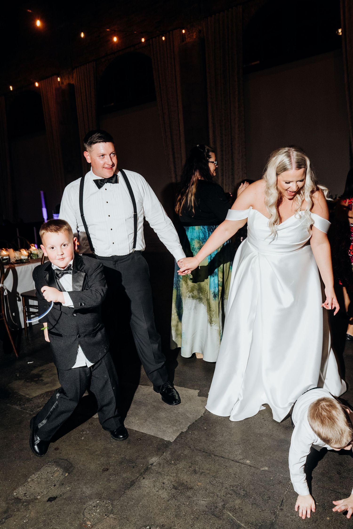 Wedding party members dancing energetically on the reception dance floor.