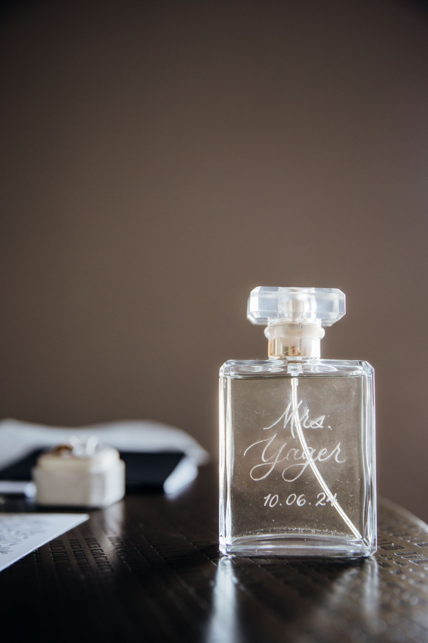 Close-up shots of engraved glass perfume bottles displaying wedding details and date.