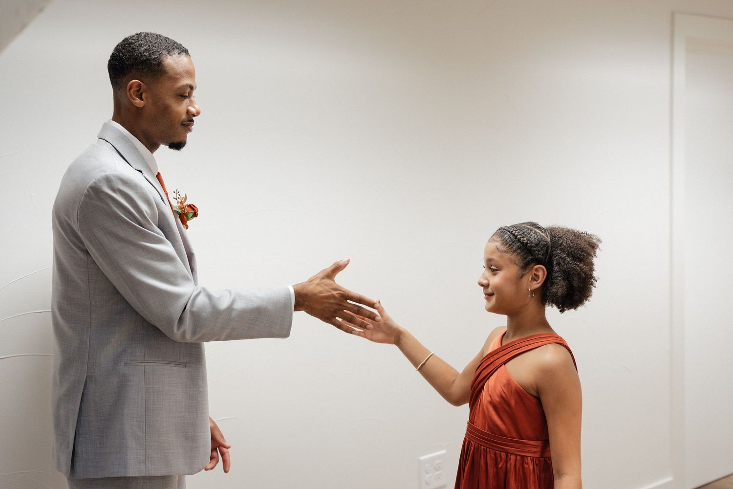 Wedding party members in gray and red attire share joyful reactions during formal photos.