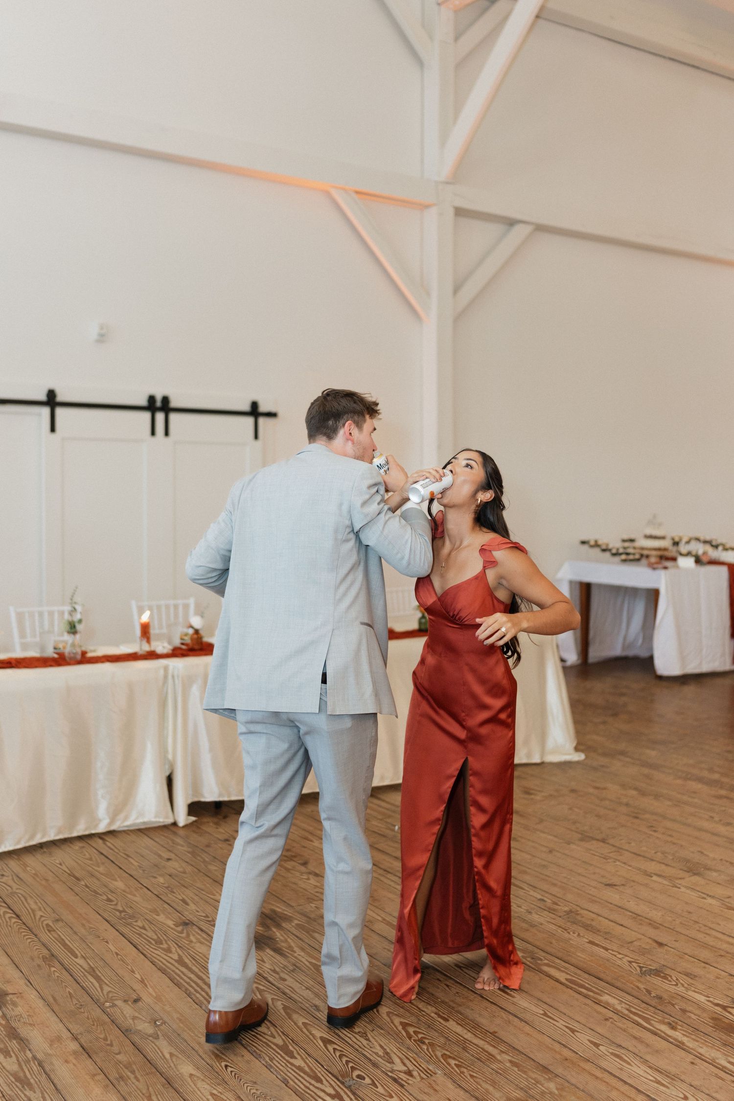 A couple dances together in a rustic indoor venue with wooden floors.