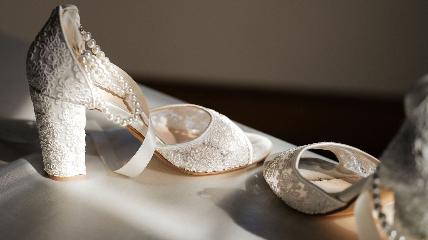 A row of elegant white lace bridal shoes arranged in a line on a neutral surface.