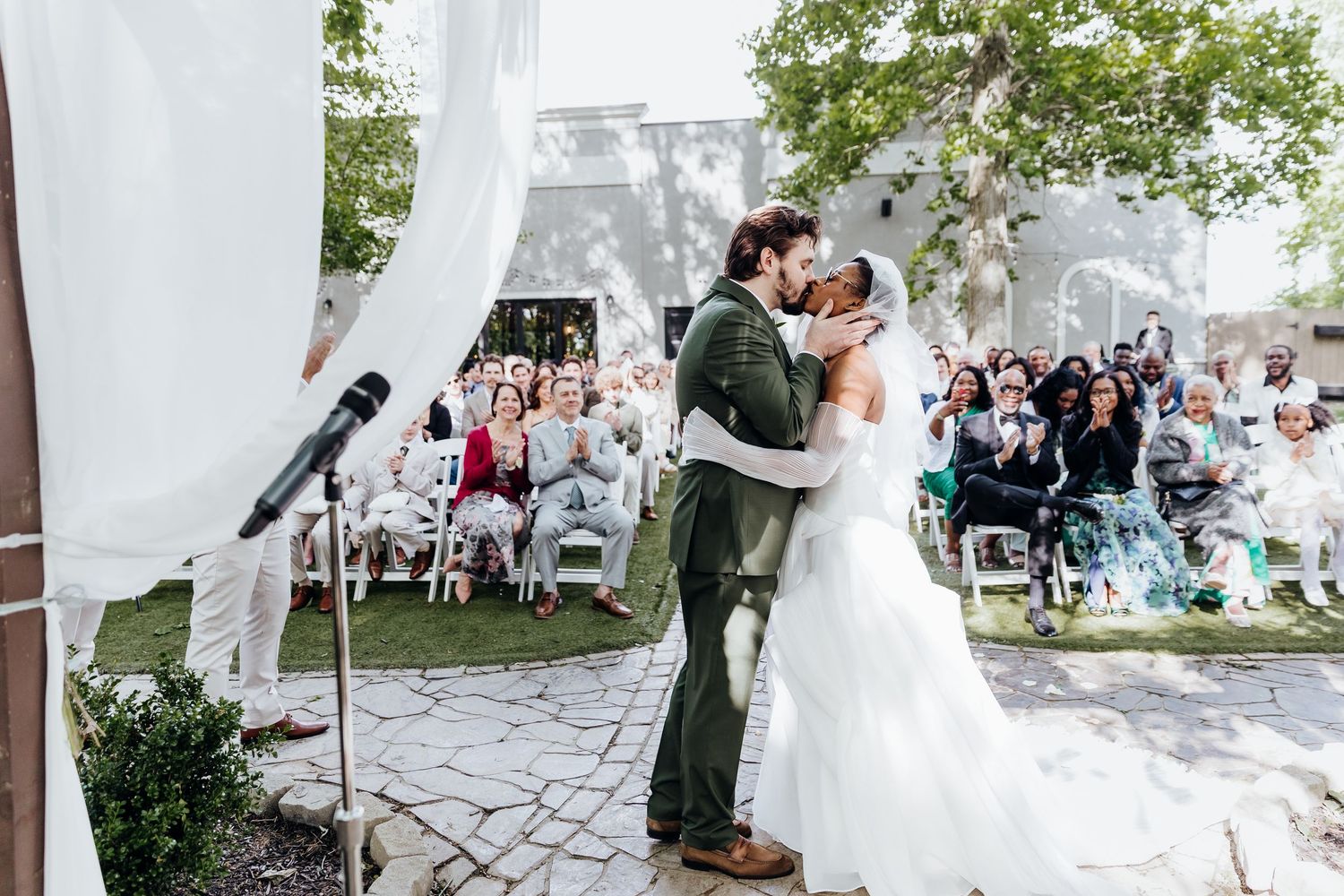 Outdoor wedding ceremony setup with white chairs and floral decorations on stone pathway.