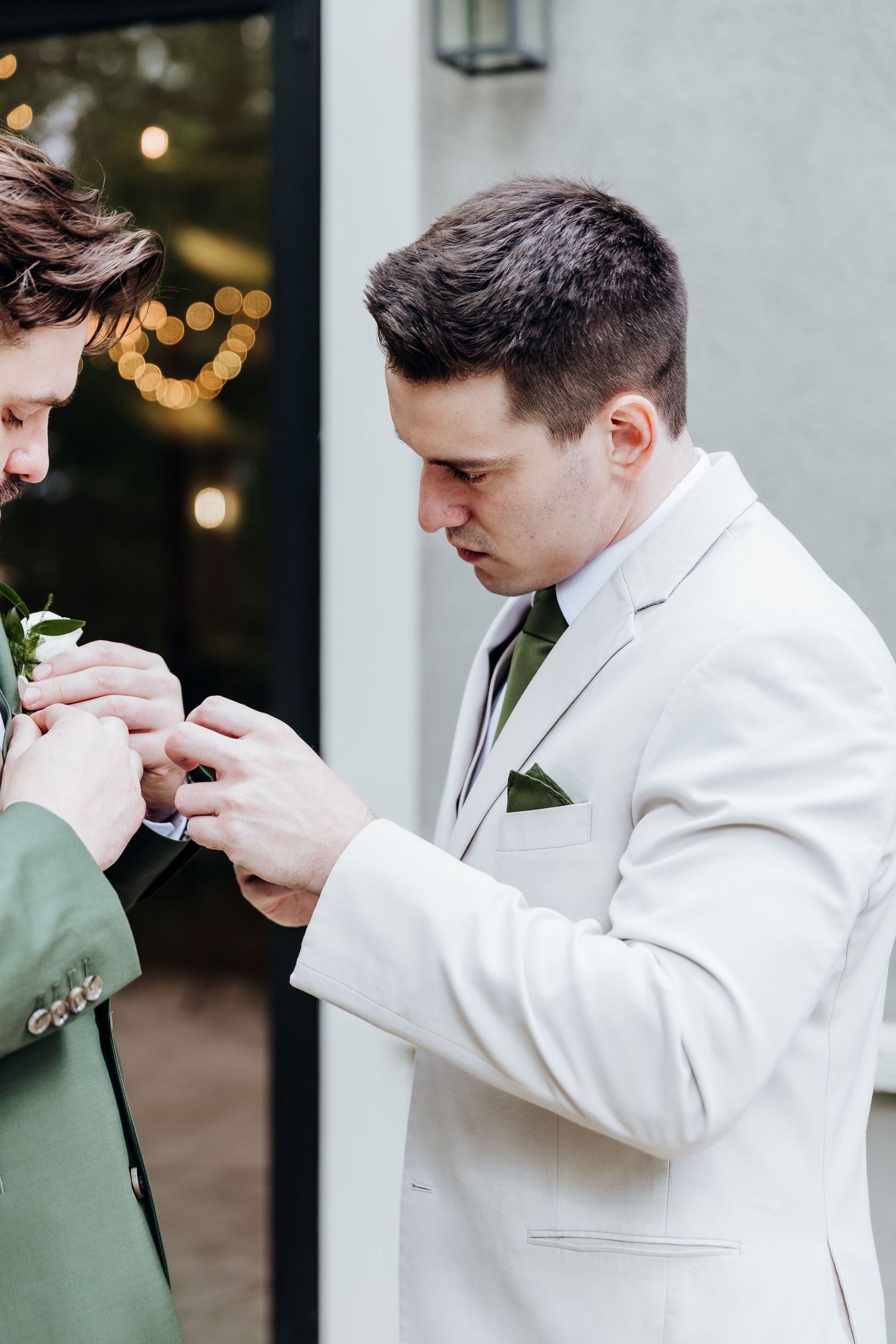 Person in white suit jacket smelling a boutonniere before the ceremony.