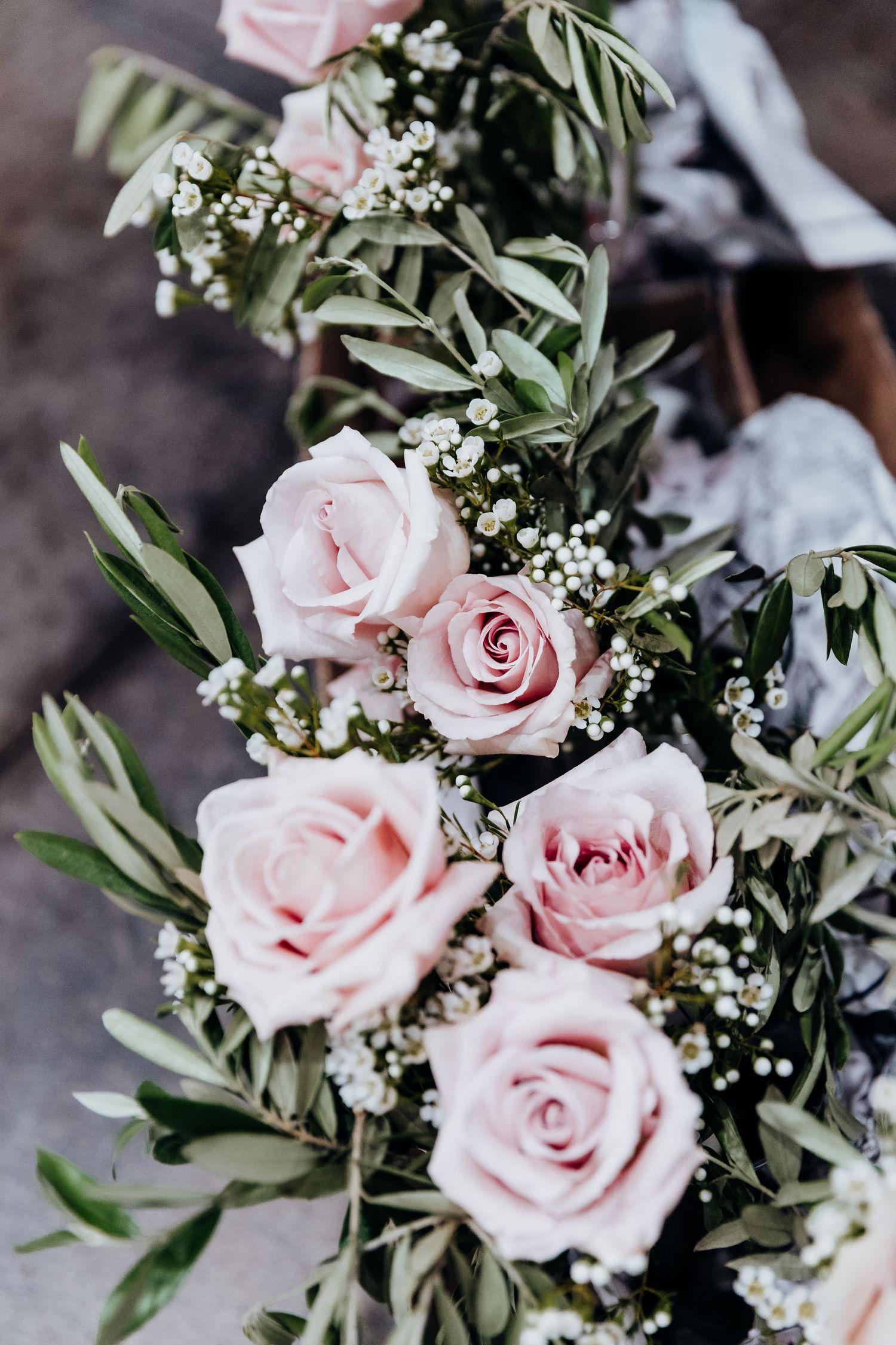 Delicate pink roses and baby's breath arranged in an elegant wedding bouquet with green foliage.