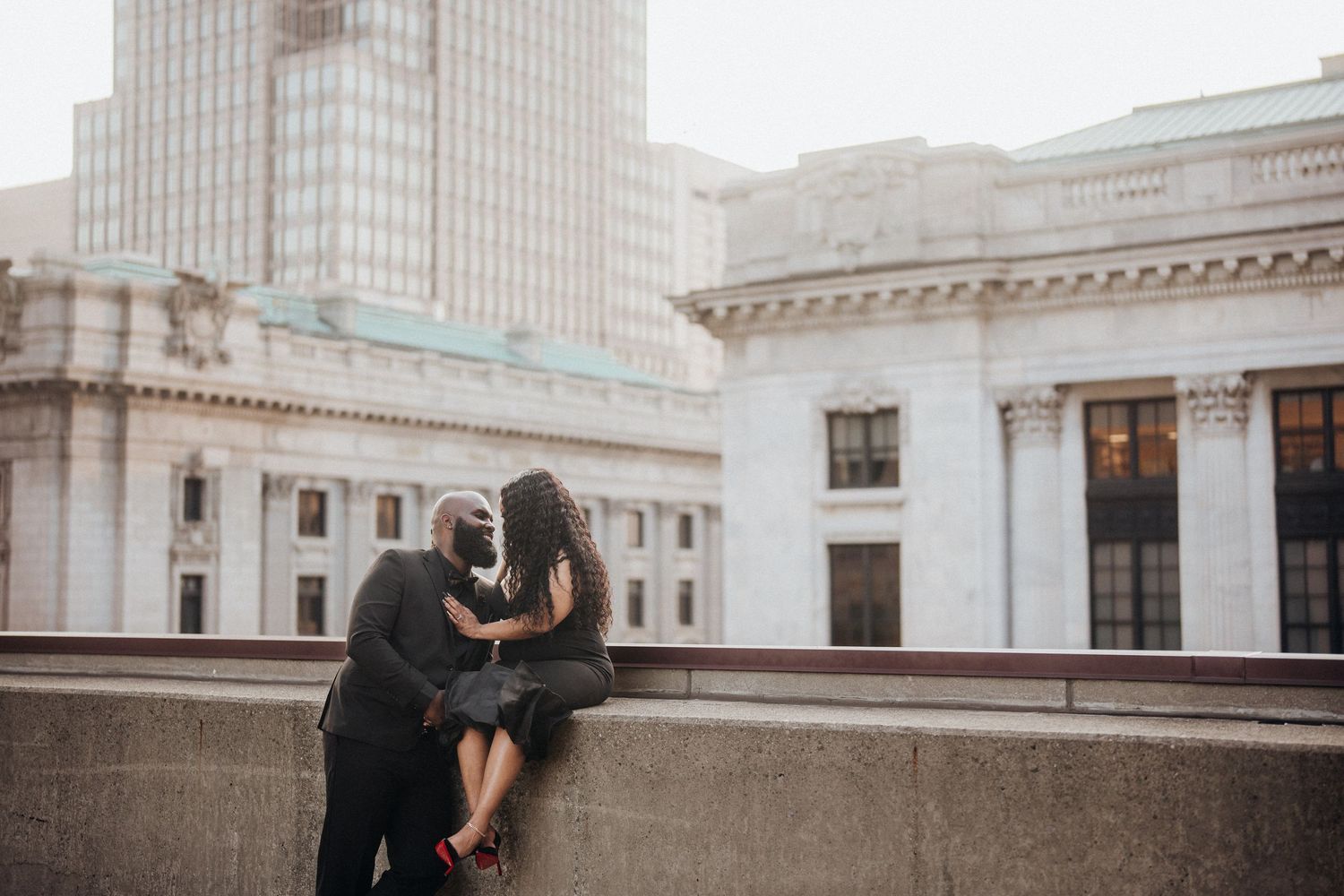 A couple shares an intimate moment on a city rooftop at dusk.