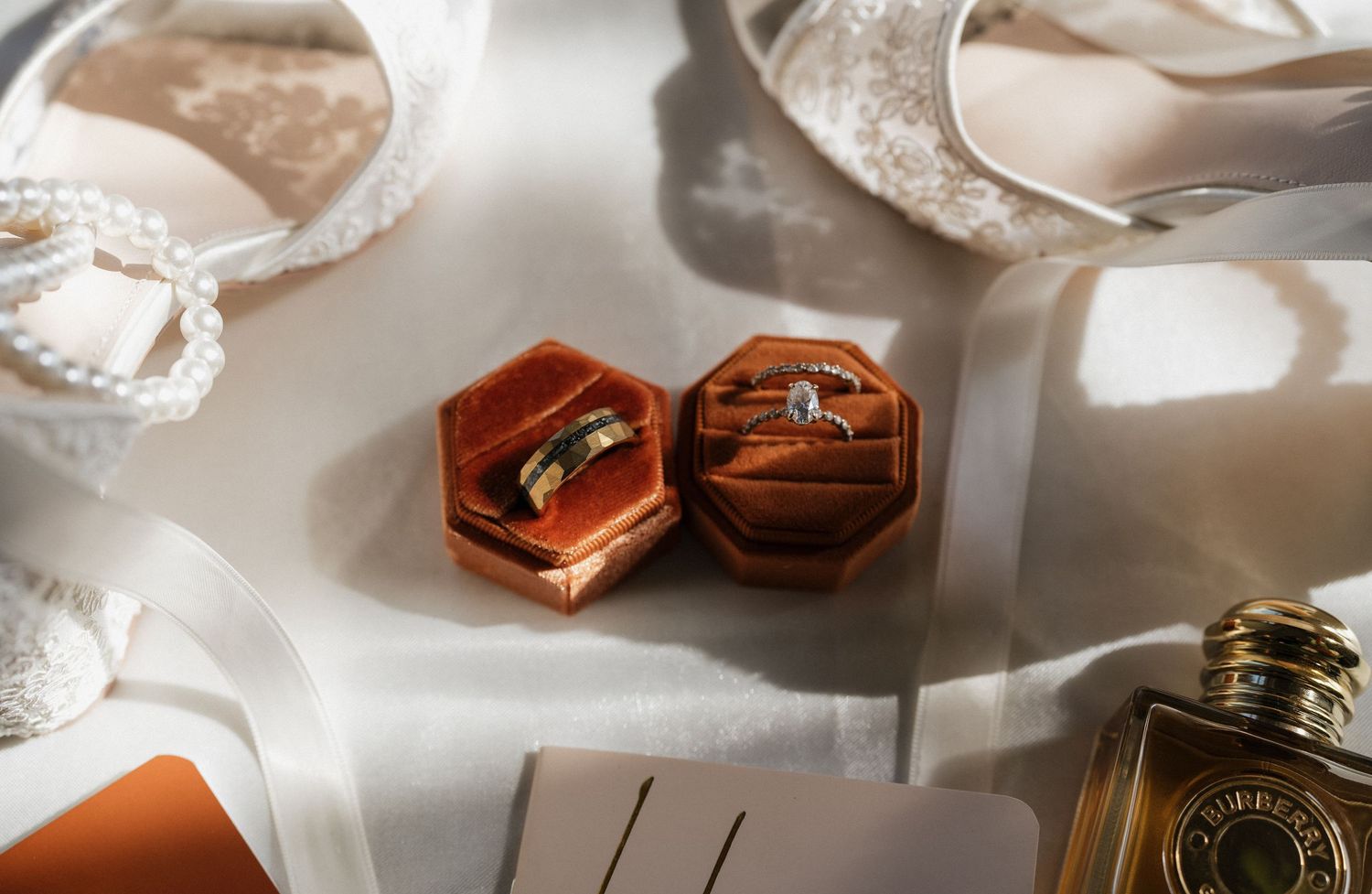 Elegant wedding details including rings, invitations, and accessories arranged on a light surface.