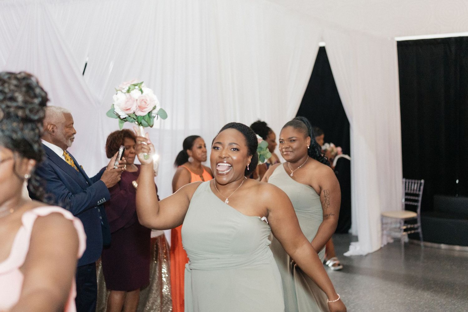Wedding reception guests dance and celebrate in an indoor venue.