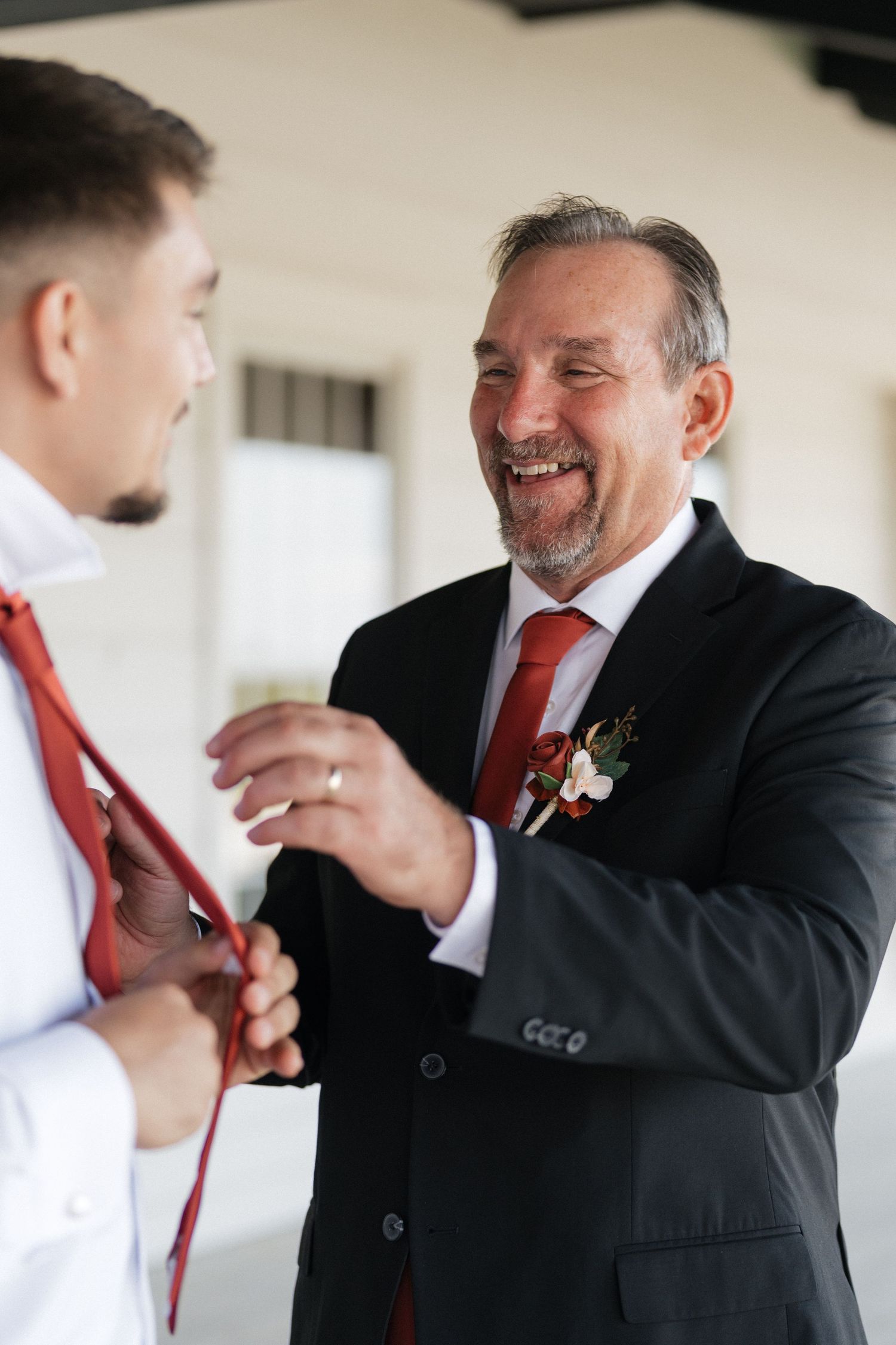 Wedding party members in formal attire share candid laughing moments during pre-ceremony preparations.