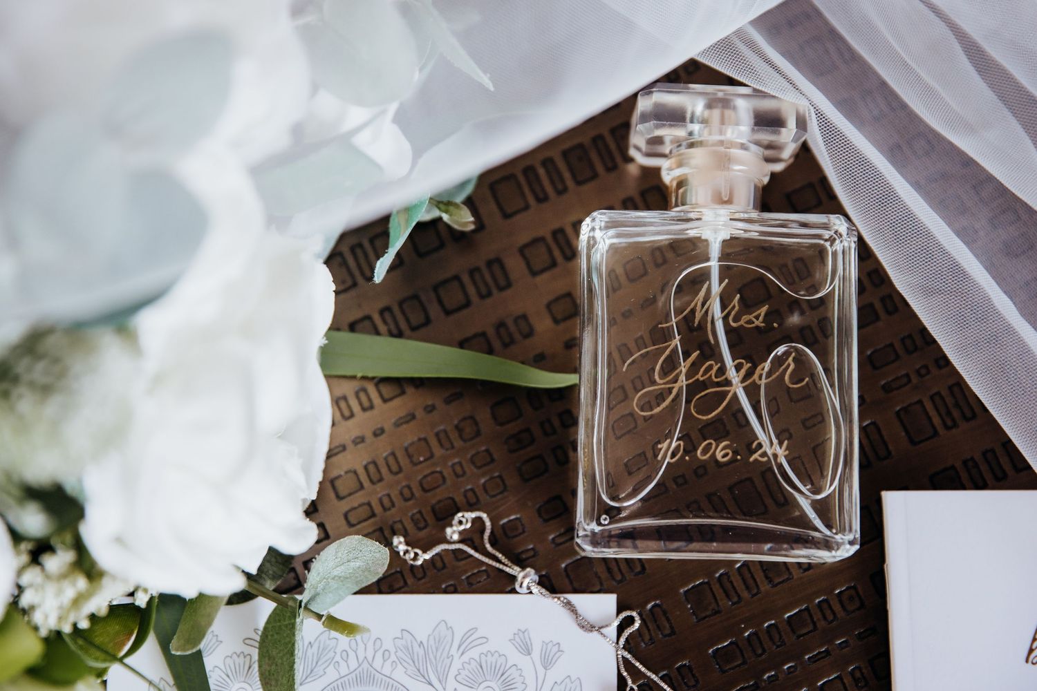 Wedding detail photo showing perfume bottles and floral arrangements in an elegant setting.