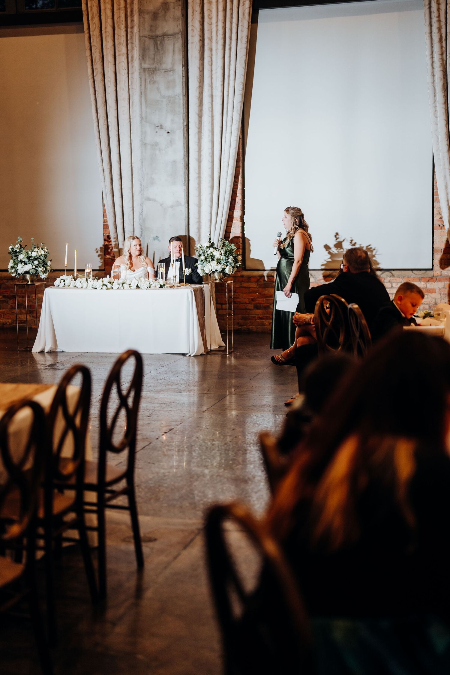 Elegant wedding reception venue with dark chairs and white drapes creating a sophisticated atmosphere.