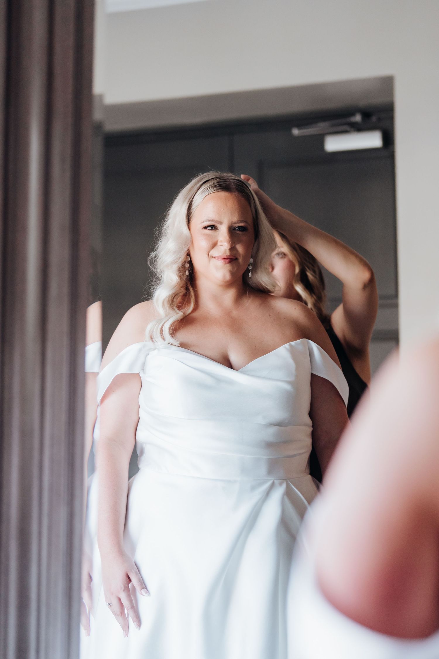 Bride getting ready in an elegant white wedding dress in a bright modern room.