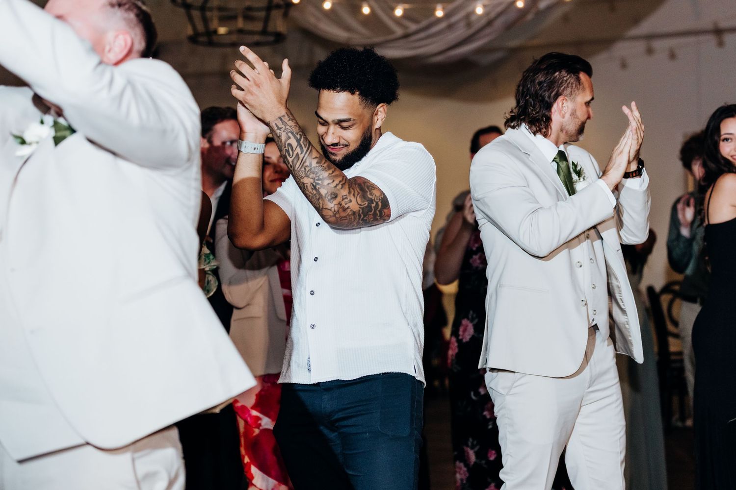 Wedding reception dance floor filled with guests in formal attire enjoying the celebration.