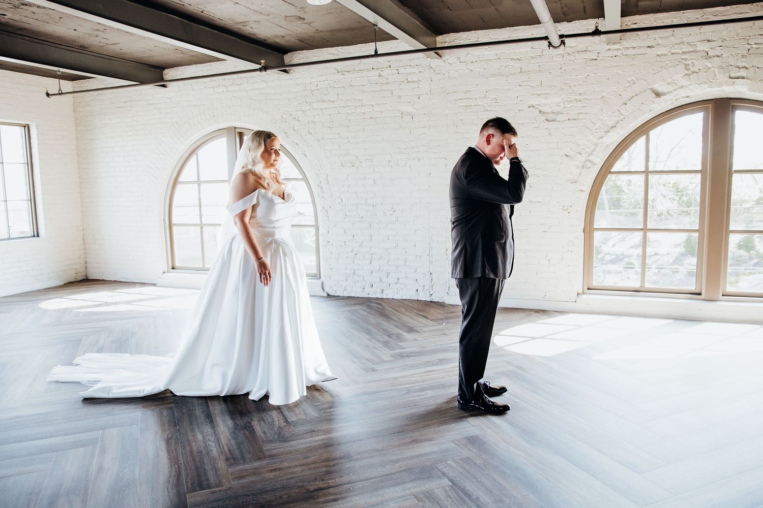 Wedding couple shares romantic moments in a spacious white industrial venue.