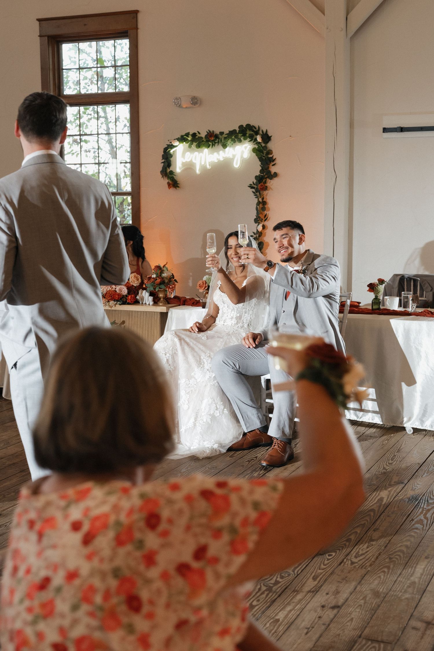 Wedding guests watch couple's first dance in rustic indoor venue with wooden floors.