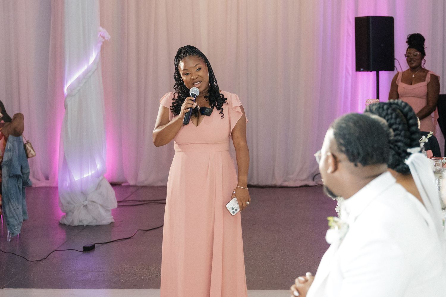 A wedding guest in pink dress performs during the reception while others watch.