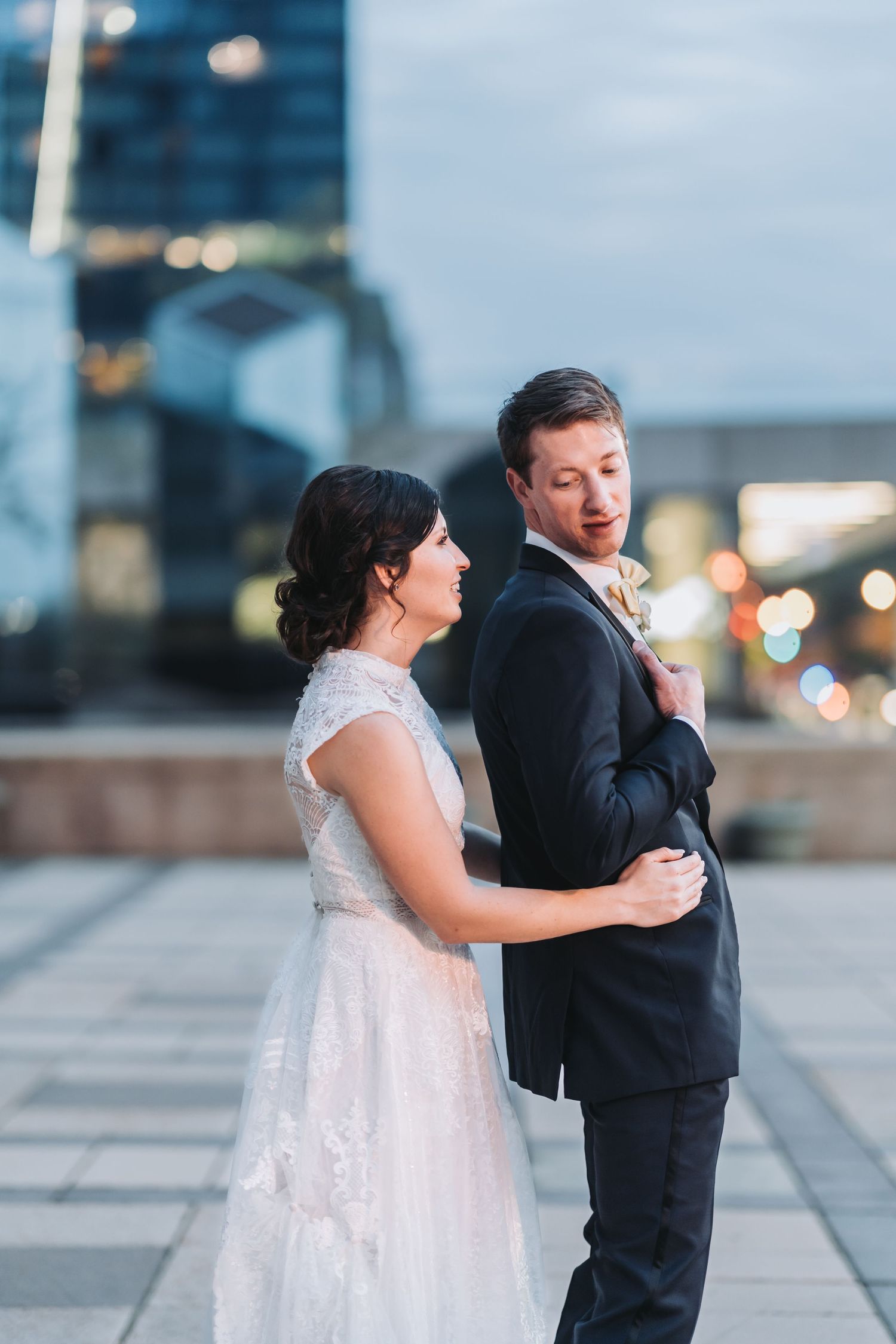 A couple shares a playful dance moment on an urban walkway at dusk.