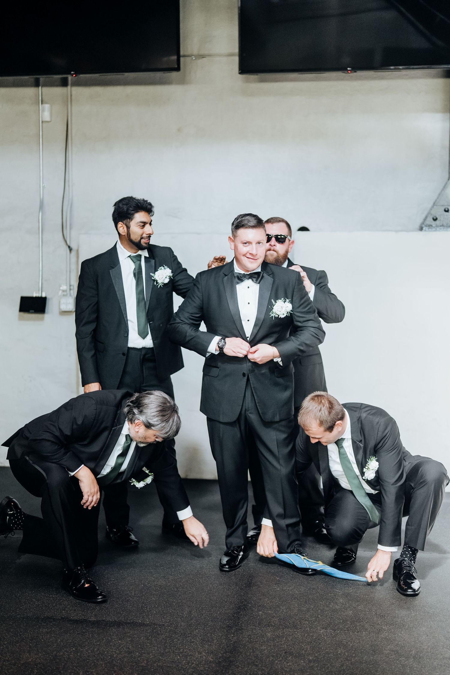 Groomsmen in formal black suits adjusting their attire before the ceremony.