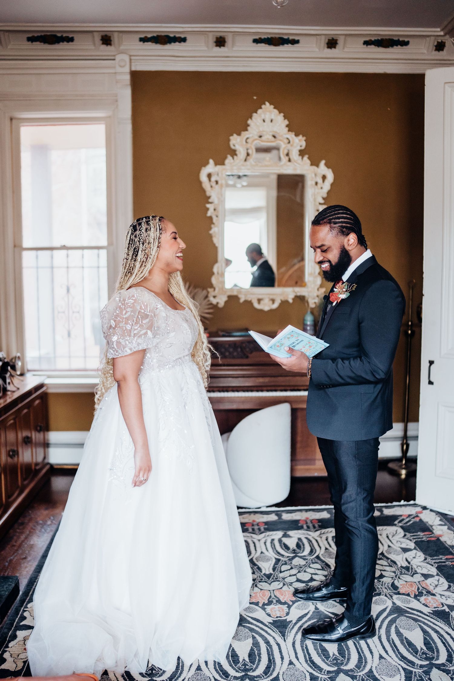 A couple shares an intimate first look moment in an elegant room with an ornate mirror and vintage decor.