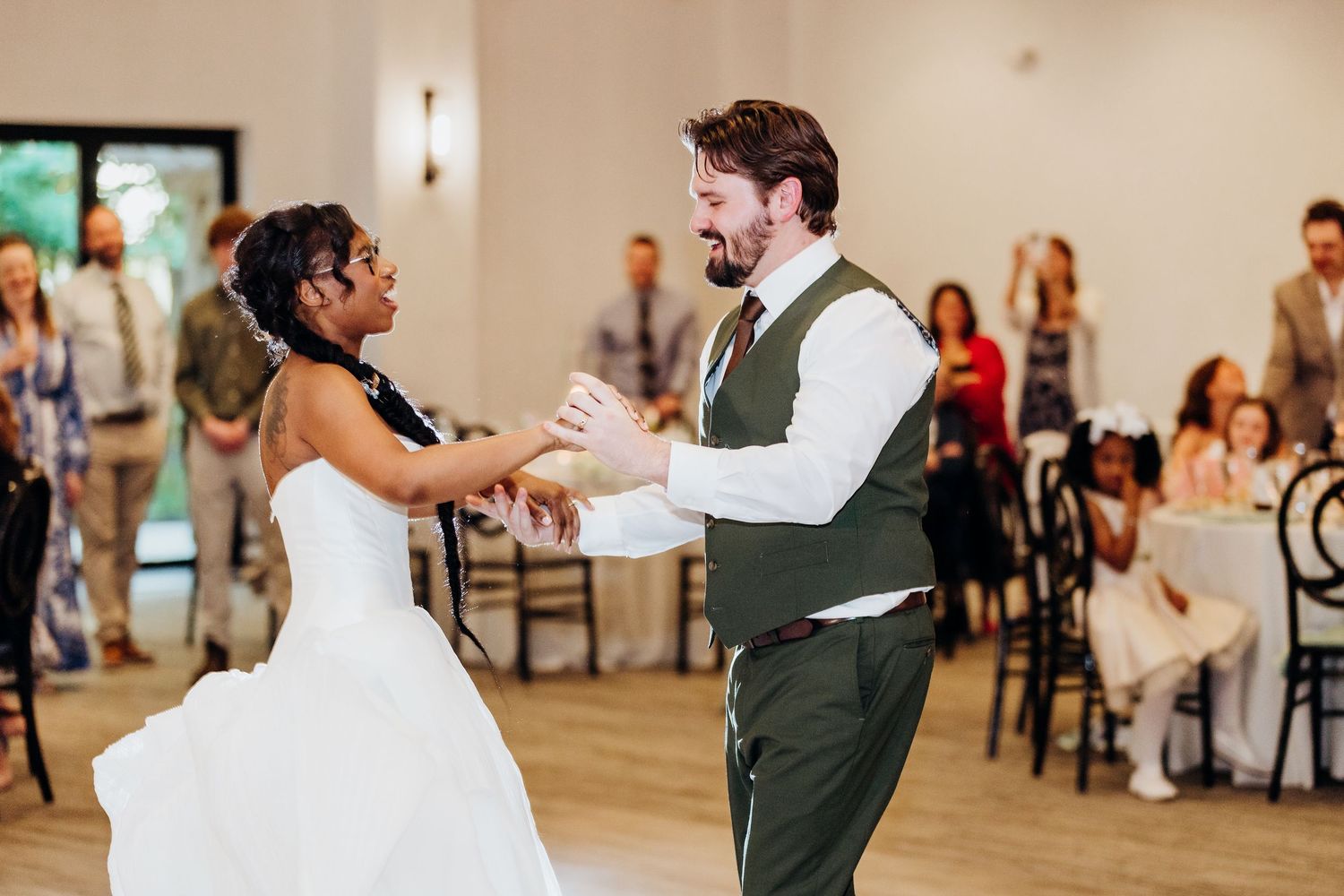 Wedding celebration dance moments captured in bright indoor venue with guests watching.