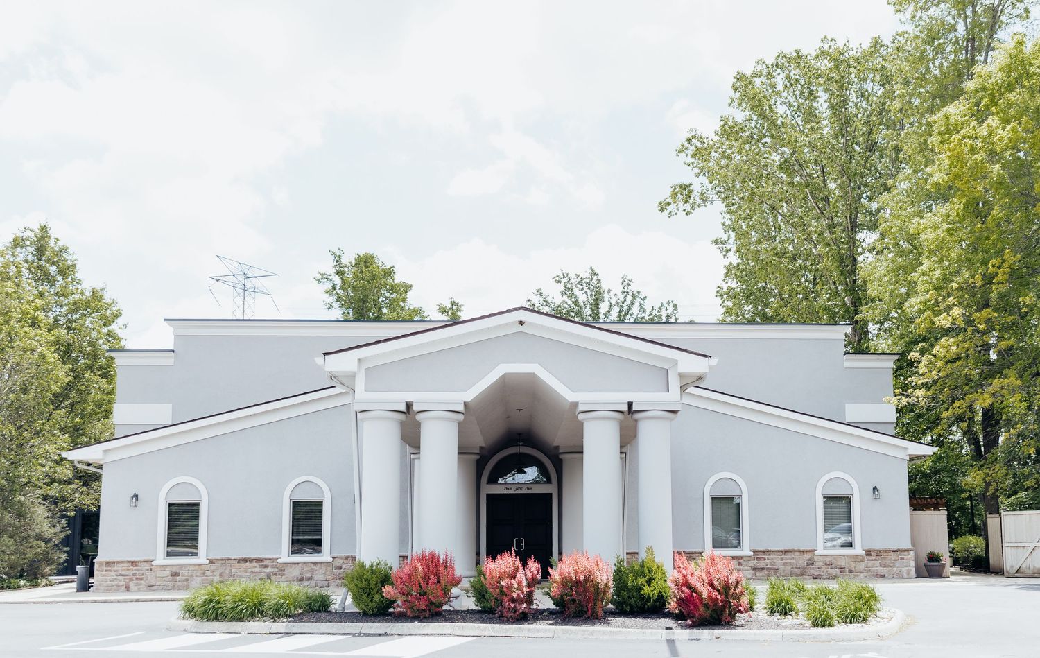 A long panoramic view of white modular buildings with red flowers and green trees against a bright sky.