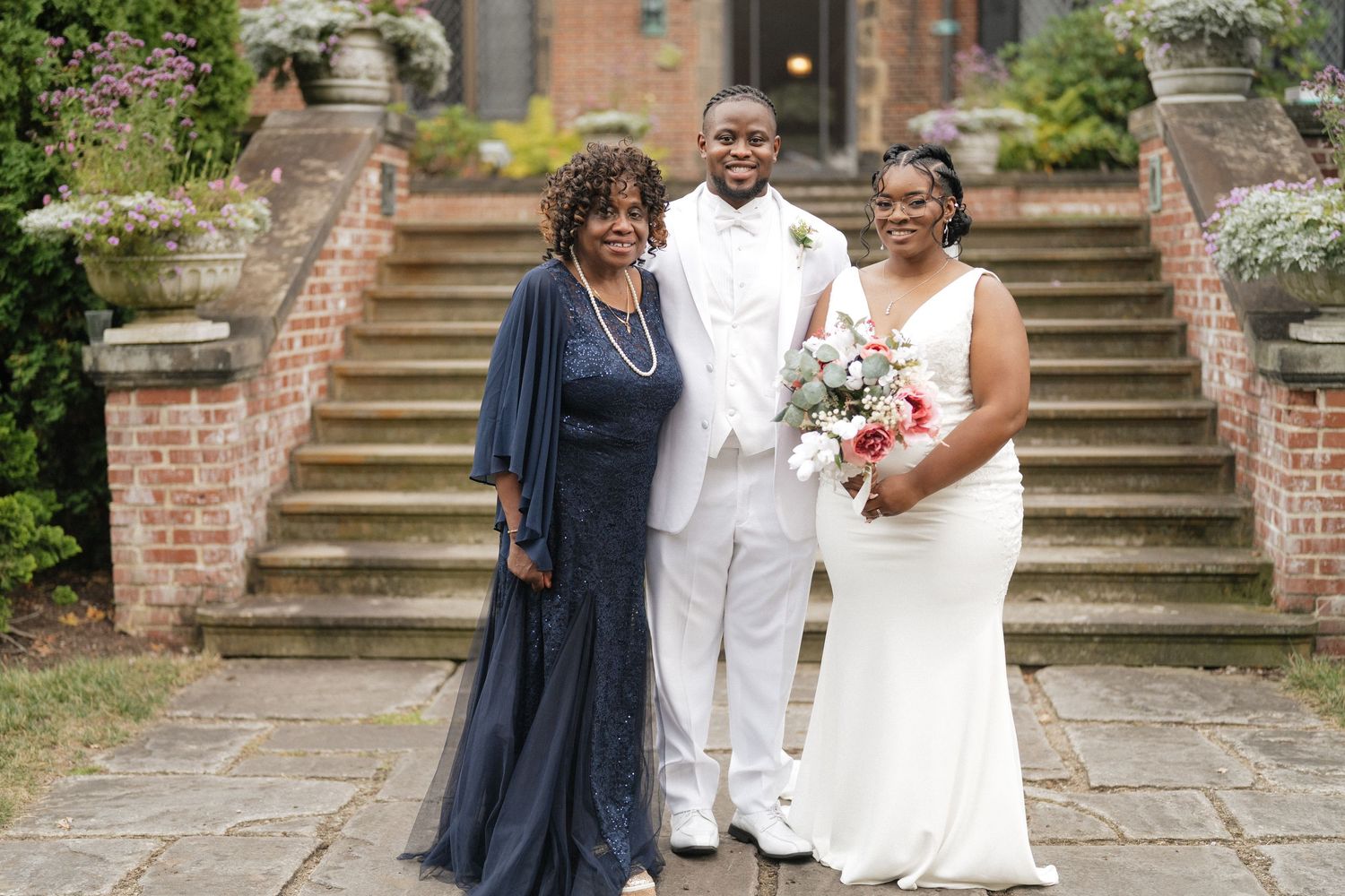 Wedding party poses on brick steps of historic garden venue.