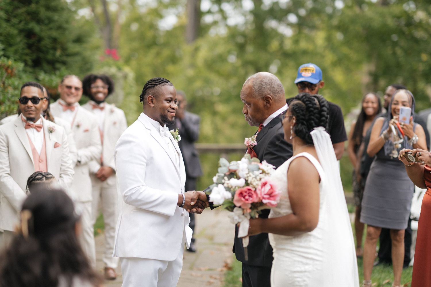 Wedding ceremony in progress outdoors with guests watching the couple exchange vows.