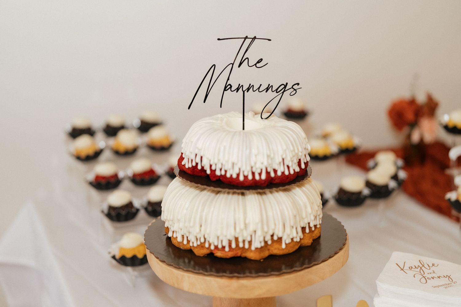 Wedding dessert display with elegant white frosted cakes on wooden stands.