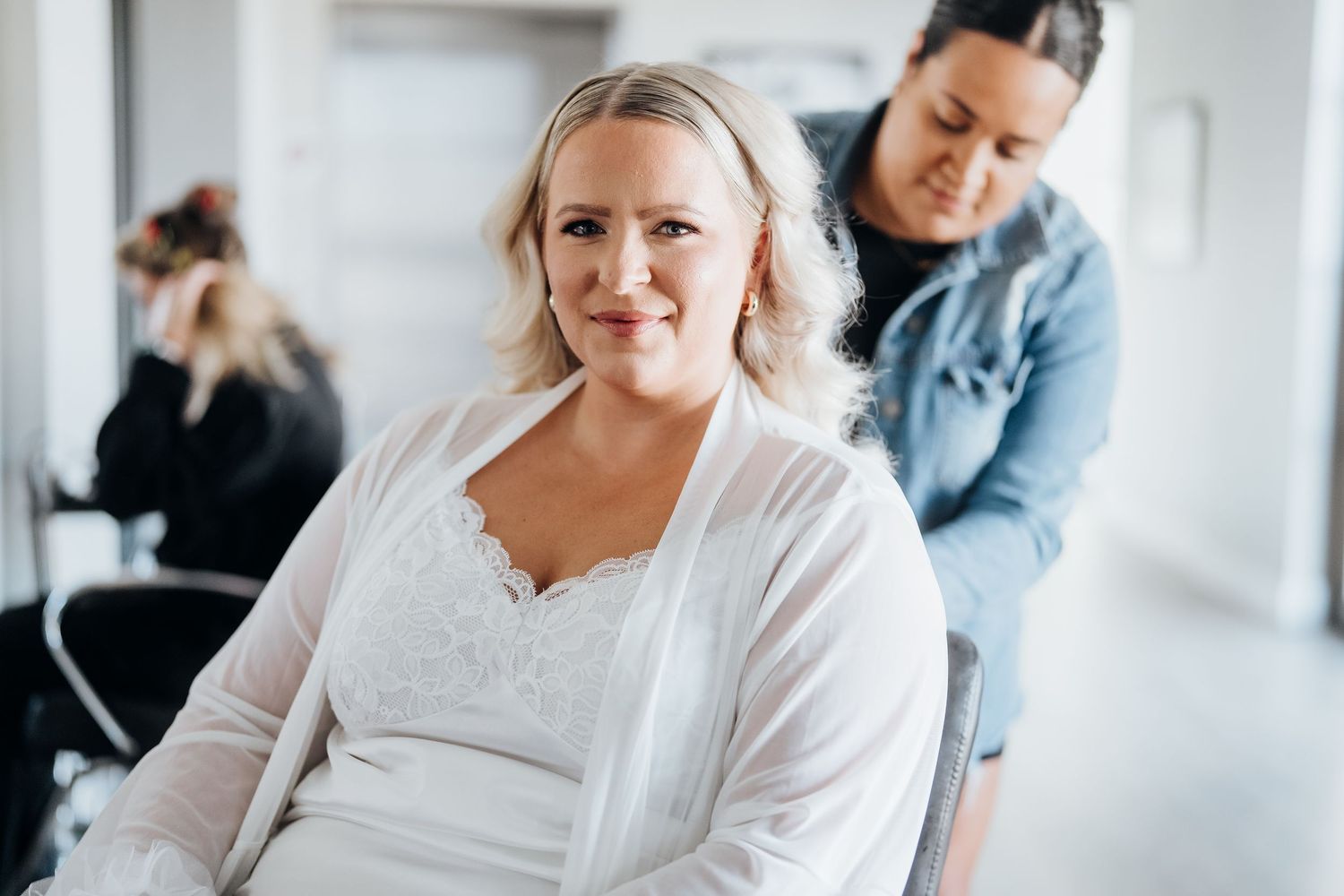 Wedding preparation scene with people getting ready in a bright white room with natural lighting.