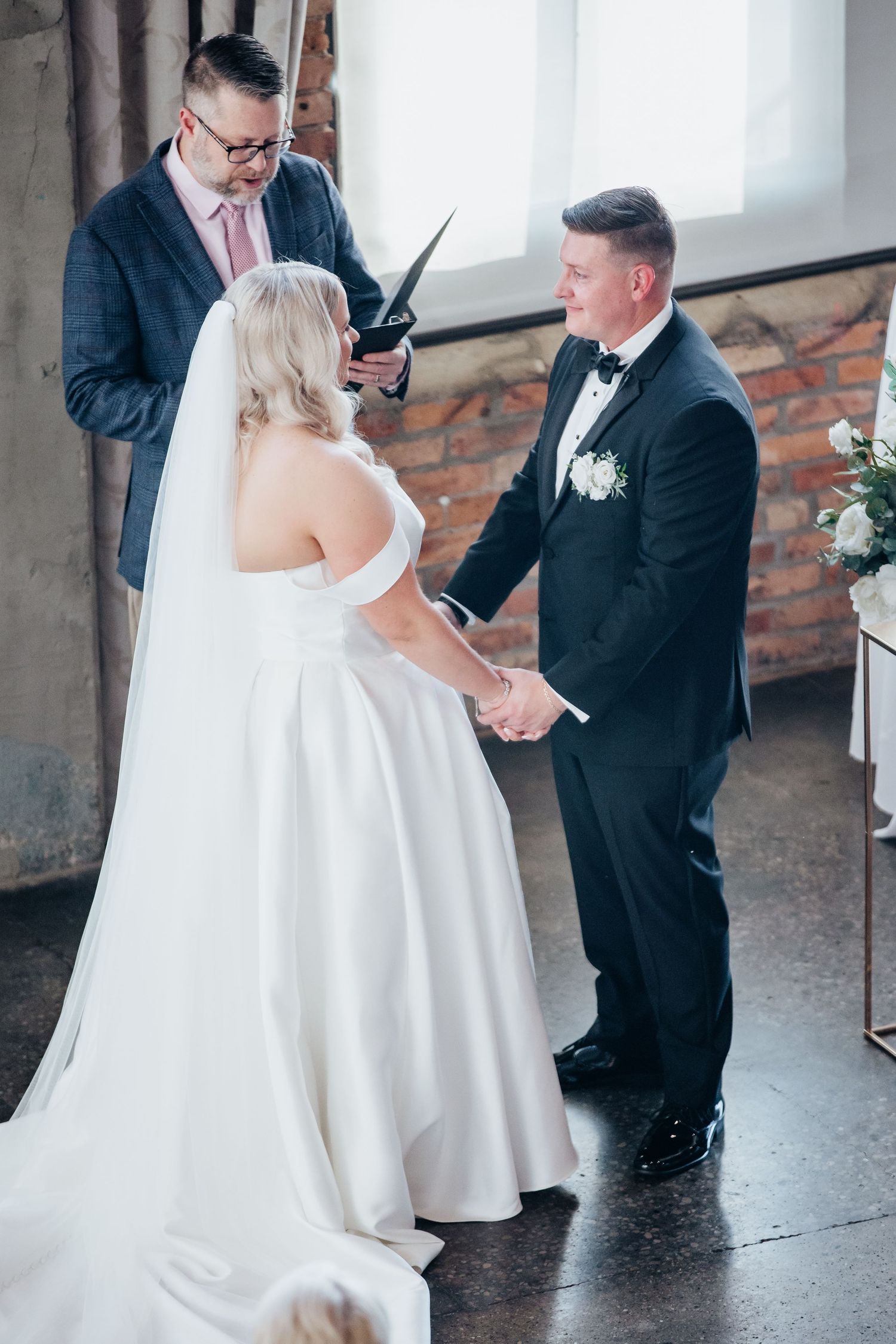 A couple shares their first dance at their wedding reception in a rustic brick-walled venue.