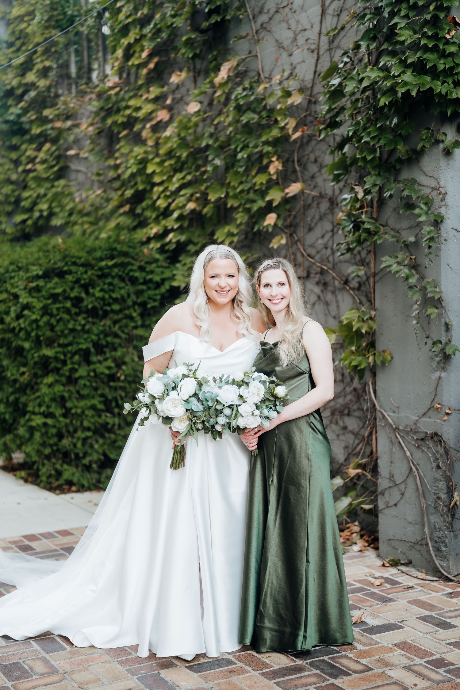 Bridal party laughs together during outdoor photo session with ivy backdrop.