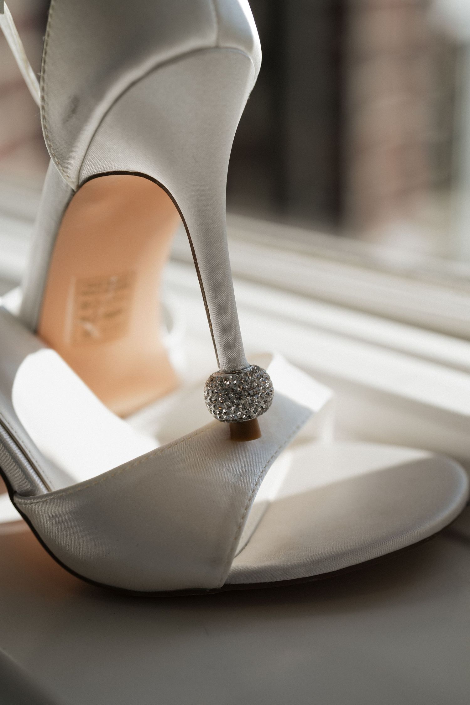 Close-up details of elegant white bridal shoes with crystal embellishments from multiple angles.
