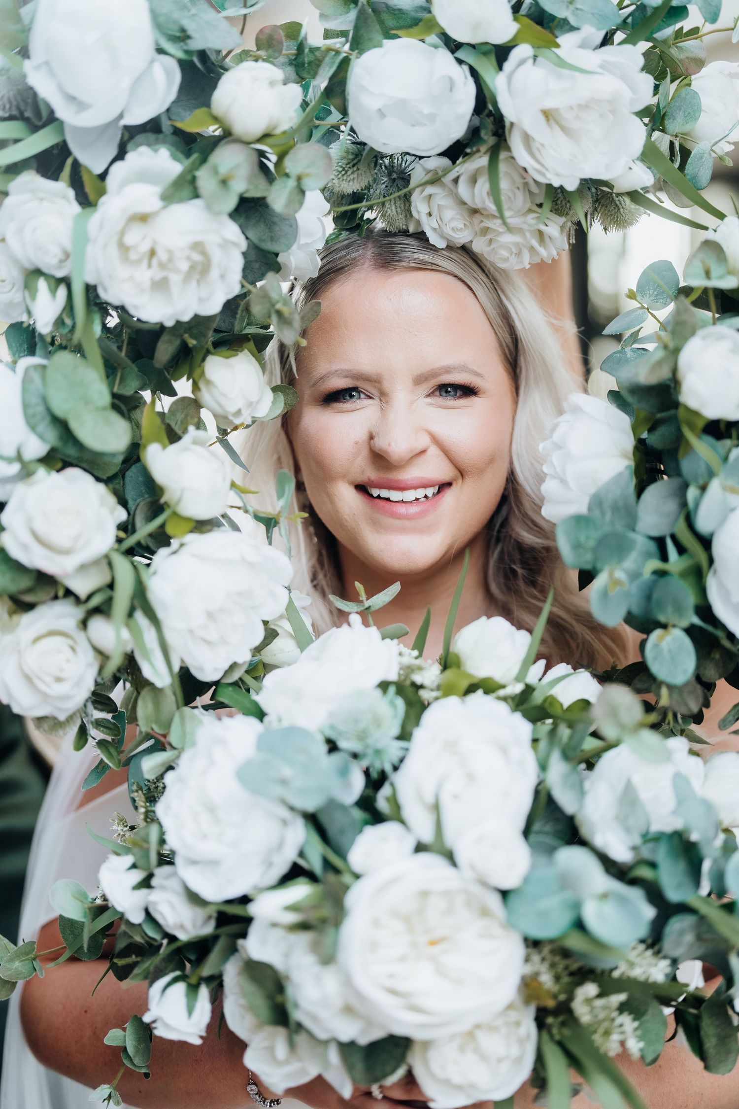 Beautiful white roses and eucalyptus create an elegant floral backdrop for wedding photos.