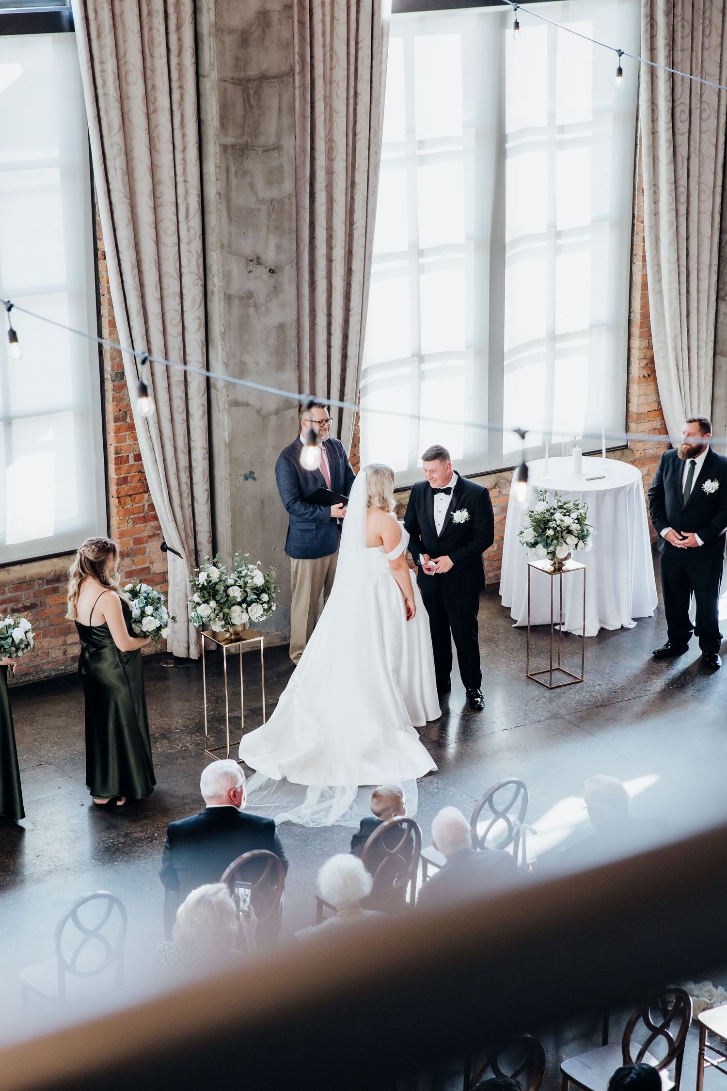 Wedding ceremony candid moments captured in an industrial venue with exposed brick walls.