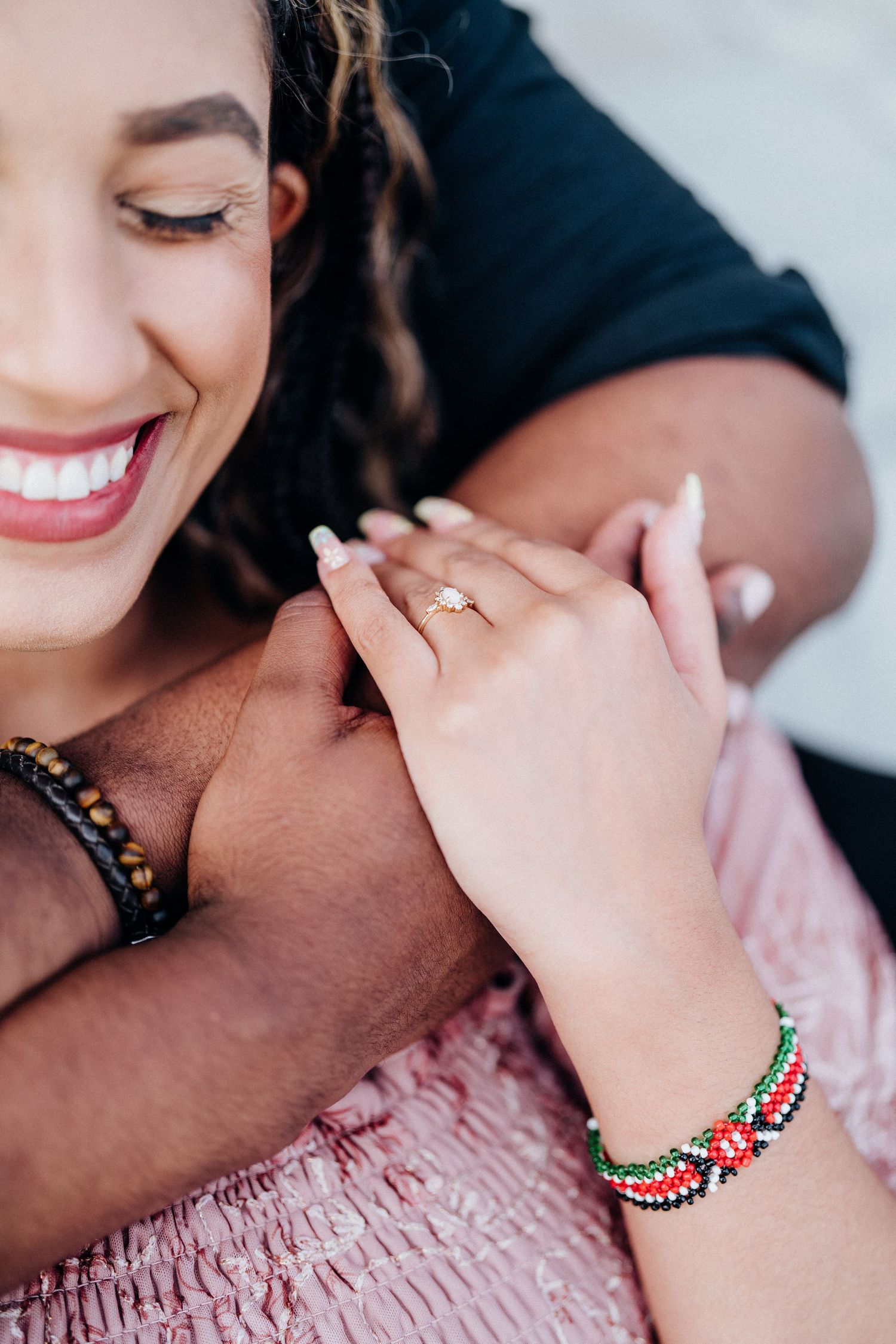 Close-up shot of engagement ring with colorful beaded bracelet detail.