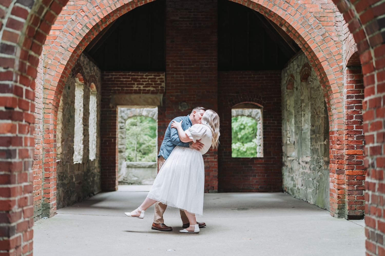 A romantic moment under a brick archway as a couple dances together.